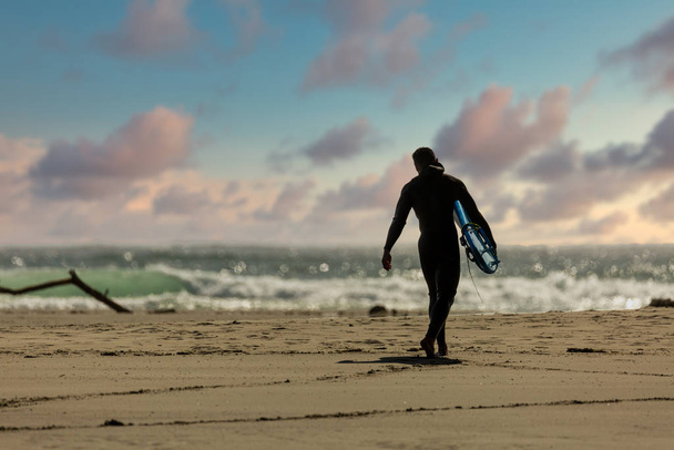 Surfers wearing wetsuits approach the green waters of Mendocino' - Fotó, kép