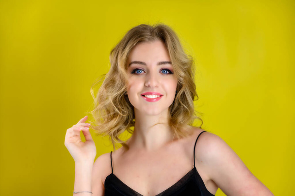 Glamorous beauty front view portrait of a pretty model with blond hair with great makeup and a beautiful hairstyle on a yellow background in the studio. The concept of cosmetics, fashion and style. - Photo, Image