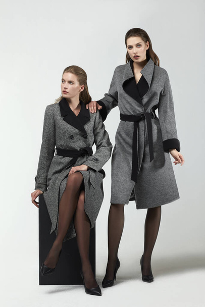 красиві модні жінки позують в елегантних пальто в студії
 - Фото, зображення
