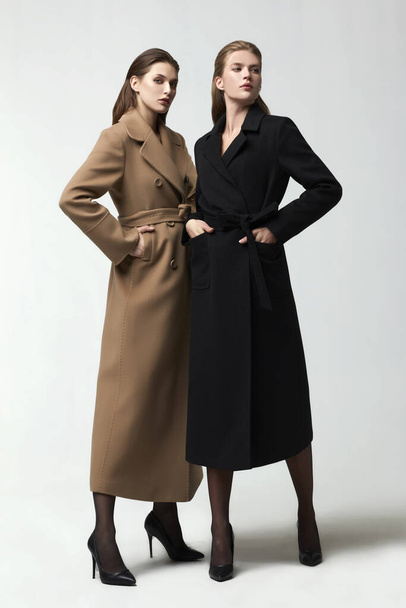 beautiful fashion women posing in elegant coats at studio - Foto, Imagen