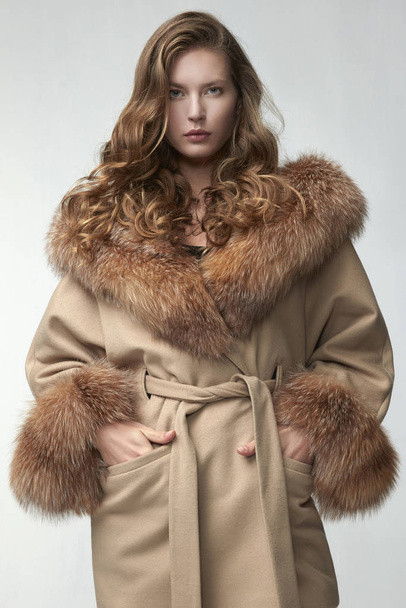 beautiful fashion woman posing in elegant coat at studio - Foto, afbeelding