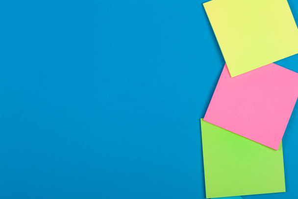 Multicolored paper reminders on a blue background. - Photo, Image