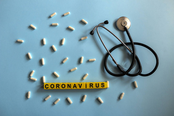 pills, stethoscope, thermometer, inhalation mask on a blue background with children`s yellow letters. Coronavirus 2019-nCoV disease and treatment concept. - Foto, Bild
