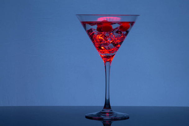 Glass of martini with ice and olives in neon light - Фото, изображение