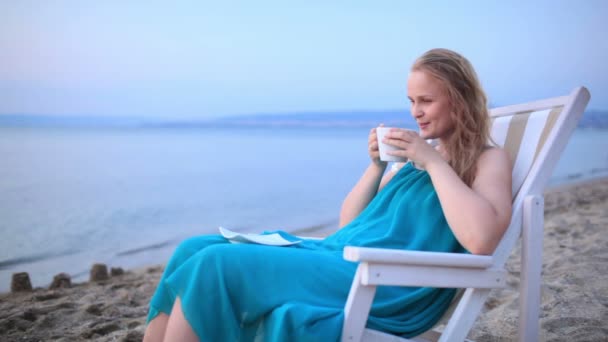 Woman enjoying a cup of tea at the seaside sitting relaxing on a deckchair - Footage, Video