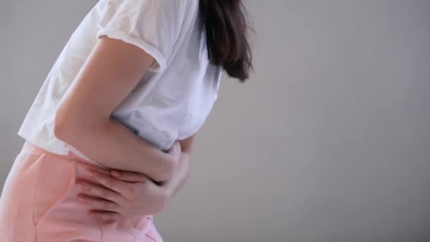 Młoda kobieta cierpiąca na ból brzucha siedząc w domu na łóżku  - Materiał filmowy, wideo