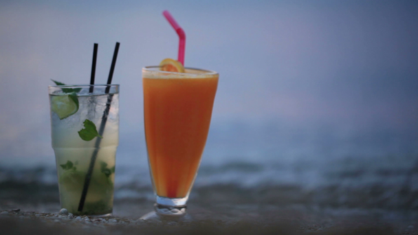 Close up shot of two fruity alcoholic cocktails mojito and orange juice - Footage, Video