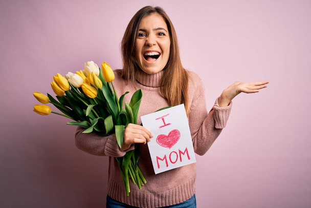 Красива жінка тримає папір з любов'ю мама повідомлення і тюльпани святкування дня матері дуже щасливий і збуджений, переможець вираження святкування перемоги кричить з великою посмішкою і піднятими руками
 - Фото, зображення