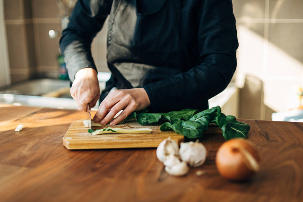 Female chef chopping raw vegetables on a wooden board - Fotoğraf, Görsel