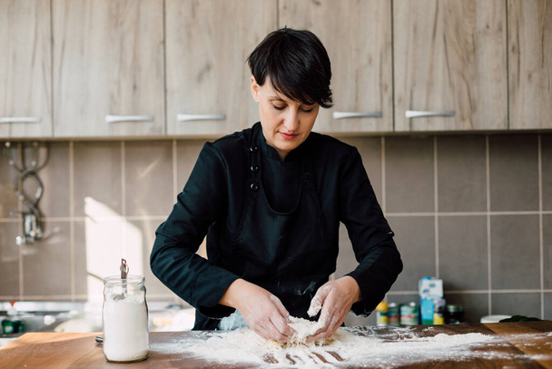 Female chef kneading dough in the kitchen - Фото, зображення