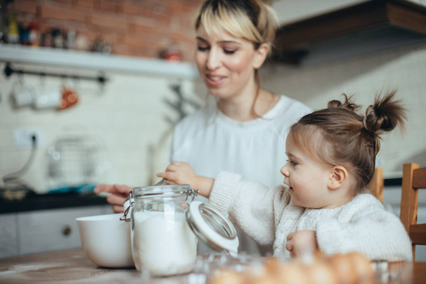 Mother and daughter baking cookies in their kitchen - 写真・画像