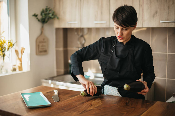 Vrouwelijke chef bereidt maaltijd met aubergine - Foto, afbeelding