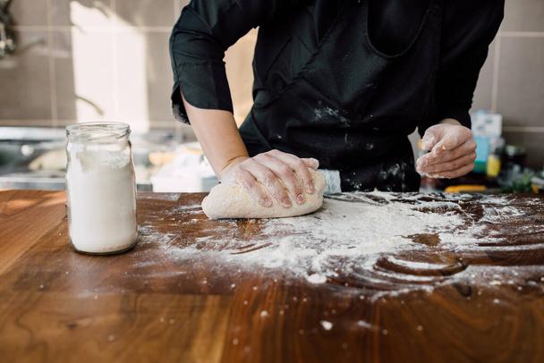 Female chef kneading dough in the kitchen - Foto, Imagen