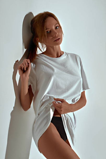atractiva modelo de mujer con ropa interior y camiseta posando sobre fondo de estudio blanco
  - Foto, imagen