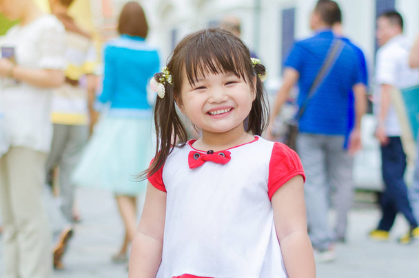 Medium schot Glimlach is oprecht van kleine meisje wit shirt en re - Foto, afbeelding