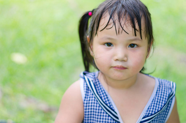 Retrato Close up A menina asiática ainda está com o rosto e tem um leve suor na testa depois de jogar playground. que olhar câmera e tem fundo verde
. - Foto, Imagem