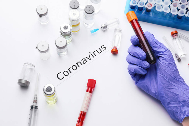 Orvos keze vérmintával és vakcinával a Coronavirus ellen fehér alapon - Fotó, kép