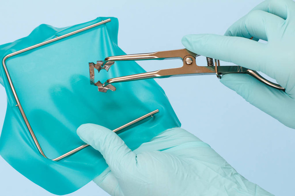 Dentist's hands in gloves with dental tongs and clasp. - Photo, Image