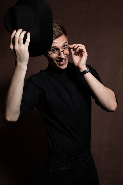 Mies pyöreissä laseissa ja musta paita hattu päässä
 - Valokuva, kuva