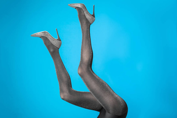Mujer con medias negras y zapatos elegantes sobre fondo azul, primer plano de las piernas
 - Foto, imagen