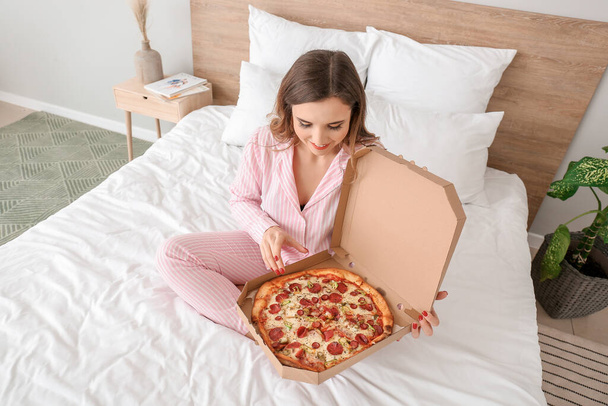 Rano piękna młoda kobieta ze smaczną pizzą w sypialni - Zdjęcie, obraz