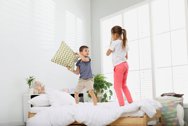 Happy children having pillow fight in bedroom - Zdjęcie, obraz