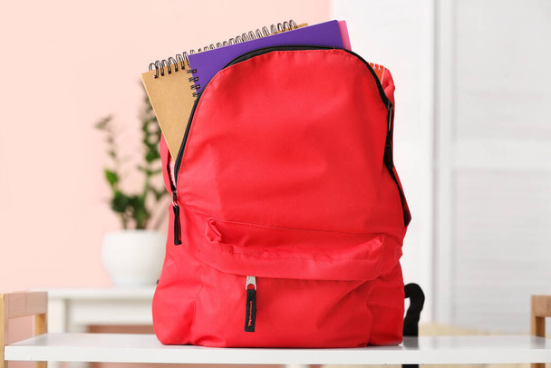 Шкільний рюкзак з канцелярським приладдям на столі
 - Фото, зображення