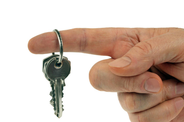Ένα μάτσο κλειδιά που κρατιούνται από ένα δάχτυλο κοντά σε λευκό φόντο  - Φωτογραφία, εικόνα