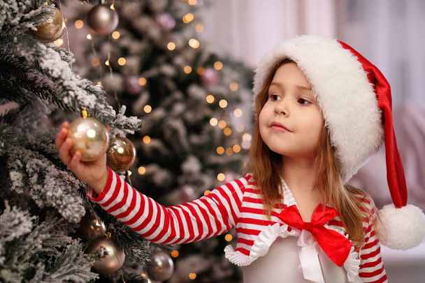 Cute little child near Christmas tree at home - Foto, Imagen