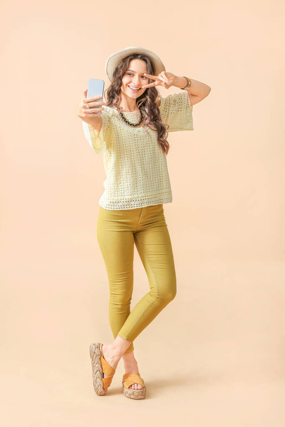Young woman taking selfie on color background - Photo, Image