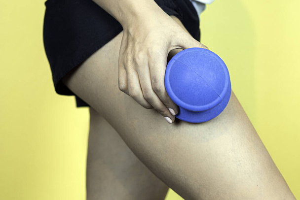 vrouw met behulp van een rubberen vacuüm beker en masseren benen voor huidverzorging op gele achtergrond. - Foto, afbeelding