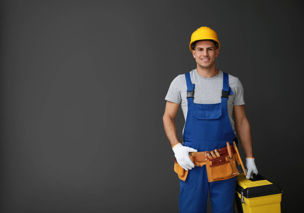 Handsome carpenter with tool box on dark background. Space for t - 写真・画像