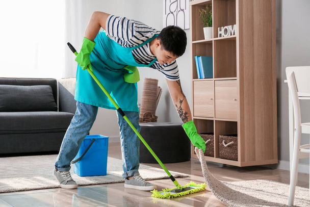 Jeune homme asiatique nettoyage plancher à la maison
 - Photo, image