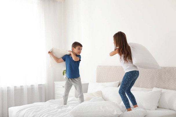 Happy children having pillow fight in bedroom - Foto, Imagen