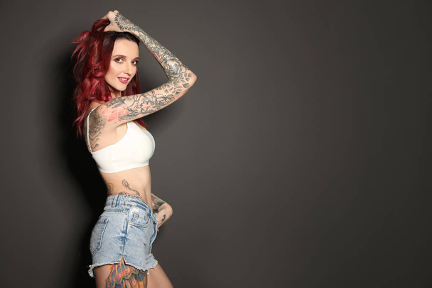 Beautiful woman with tattoos on body against black background. Space for text - Foto, afbeelding