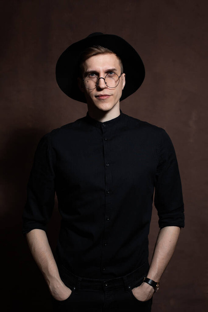 Mies pyöreissä laseissa ja musta paita hattu päässä
 - Valokuva, kuva