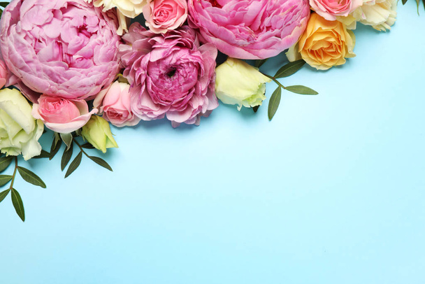 Composición plana con hermosas flores y espacio para texto sobre fondo azul claro. Diseño de tarjetas florales
 - Foto, Imagen
