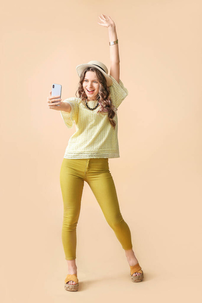 Young woman taking selfie on color background - Foto, afbeelding