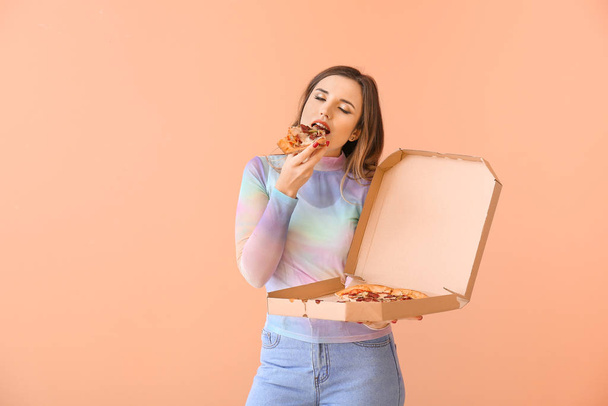 色の背景にピザを食べる美しい若い女性の肖像画 - 写真・画像
