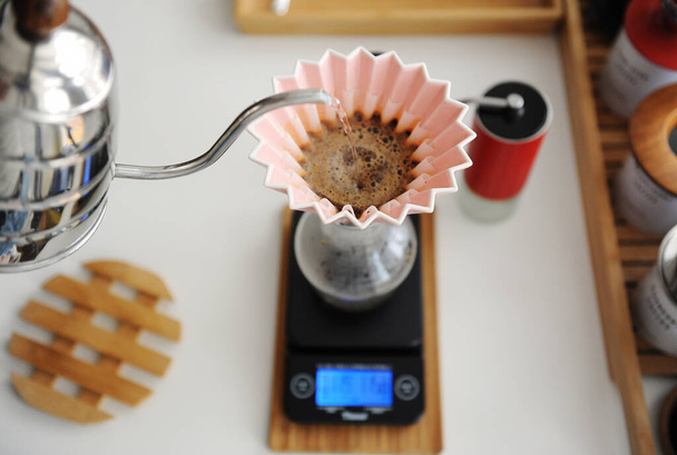 Fabricação de cerveja manual alternativa. Despejar água no café em gotejador de origami rosa com filtro de papel ondulado. Vista superior
 - Foto, Imagem