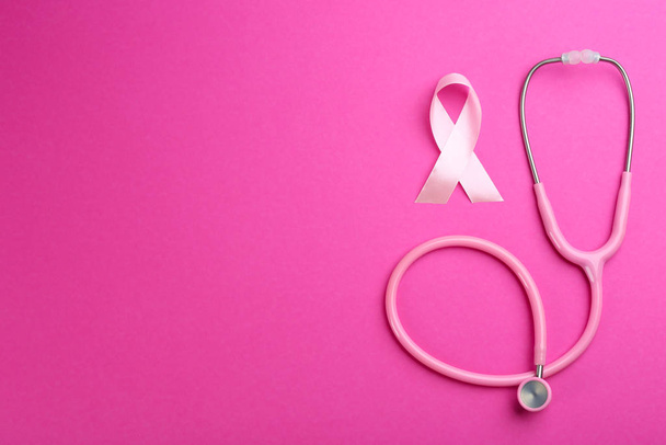 Pink ribbon as breast cancer awareness symbol and stethoscope on color background, flat lay. Space for text - Foto, Imagen