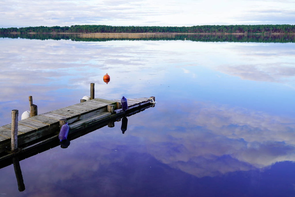 Зеркальное изображение Влияние отражения неба воды на деревянное понтонное озеро Сангине в Ланде Франция
 - Фото, изображение