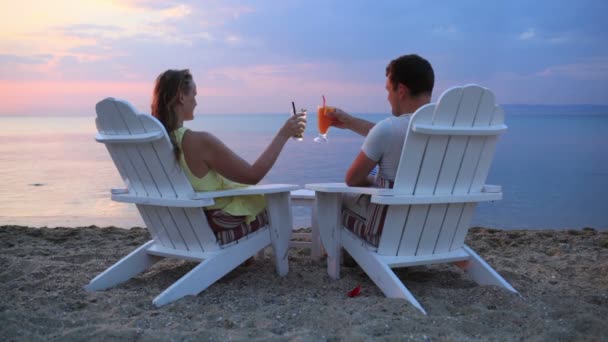 ρομαντικό ζευγάρι συνεδρίαση σε ξύλινες ξαπλώστρες στην παραλία - Πλάνα, βίντεο