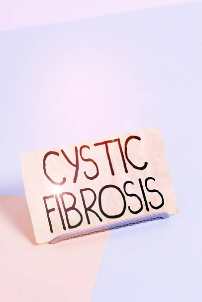 Koncepční rukopis ukazující cystickou fibrózu. Koncept znamená dědičnou poruchu postihující exokrinní žlázy Papír na tlumivkovém drátu na měkkém pastelovém vícebarevném pozadí - Fotografie, Obrázek