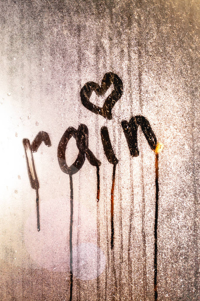 Okno z kroplami deszczu. Zdjęcie stockowe napis na mokrym szkle. - Zdjęcie, obraz