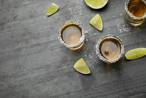 Mexican Tequila shots, lime slices and salt on grey table, flat lay - Photo, image