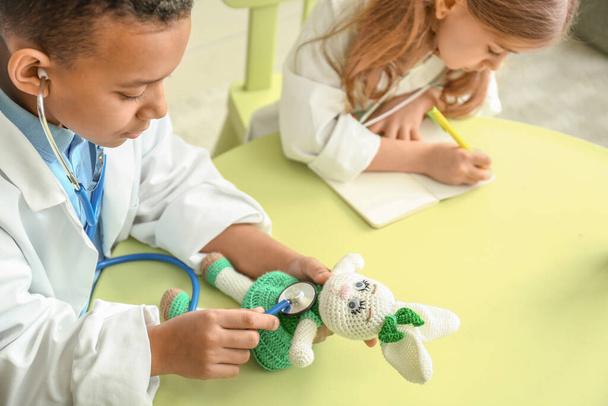 Милі маленькі діти, одягнені, як лікарі грають вдома
 - Фото, зображення