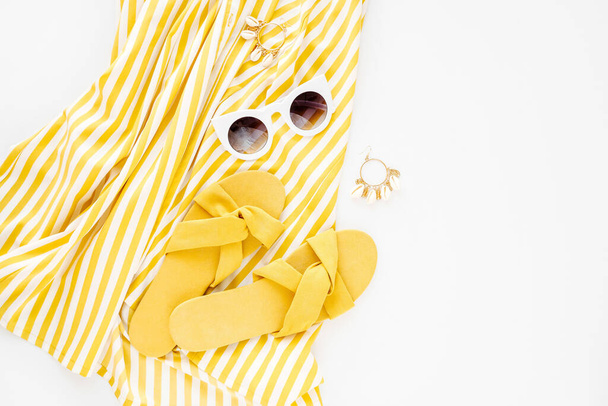 Yellow dress with stripes with slippers and sunglass. Women's stylish summer outfit. Trendy clothes. Flat lay, top view. - Foto, immagini