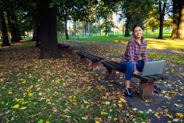 Happy hipster young woman working on laptop in the park - Фото, изображение