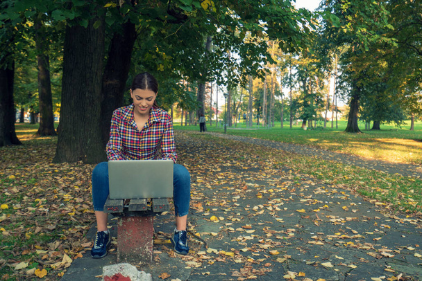 Happy hipster young woman working on laptop in the park - Valokuva, kuva